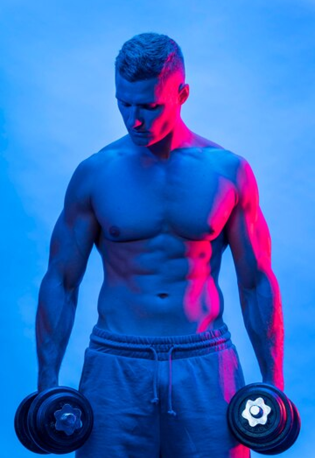 Спортивный мужина держит в руках гантели